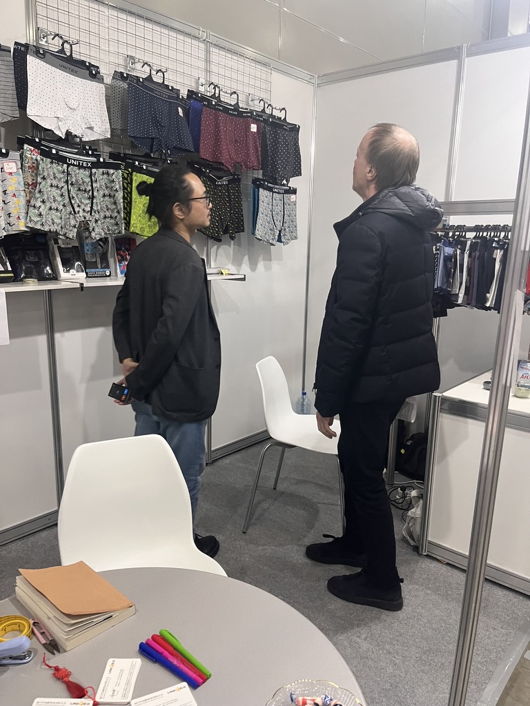 A visitor reviewing hanging underwear samples inside the Unitex booth